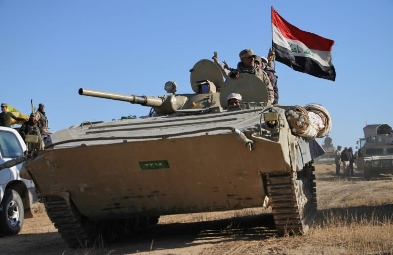 Iraqi forces flash the victory sign as they and members of the Hashed al-Shaabi (Popular Mobilisation units), advance against IS in the northern Iraqi region of al-Hadar, 105 kilometers south of Mosul, on November 23, 2017