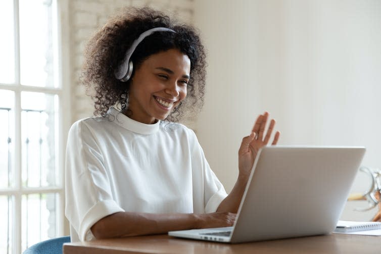 Woman waving to computer screen