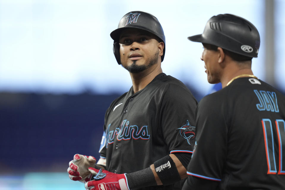 Miami Marlins' Luis Arraez, left, looks toward the stands as he listens to first base coach Jon Jay (11) following a base hit against the Kansas City Royals during the third inning of a baseball game Wednesday, June 7, 2023, in Miami. (AP Photo/Peter Joneleit)