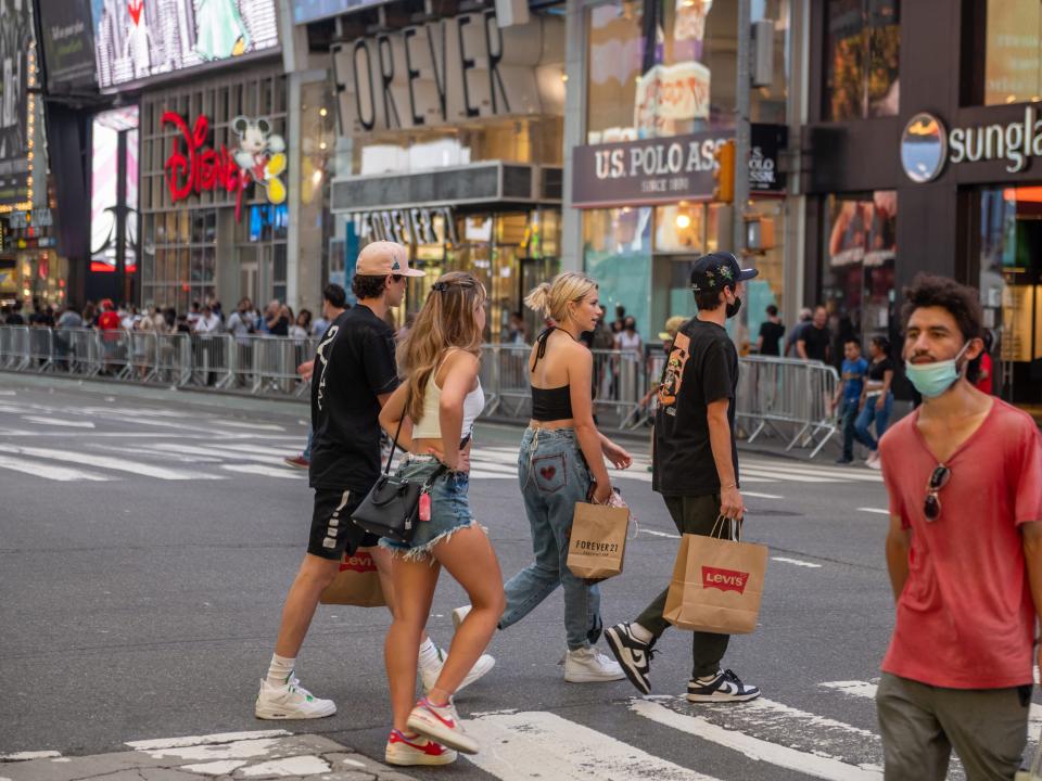 Tourists carrying shopping bags walk through Times Square on August 10, 2021, in New York City.