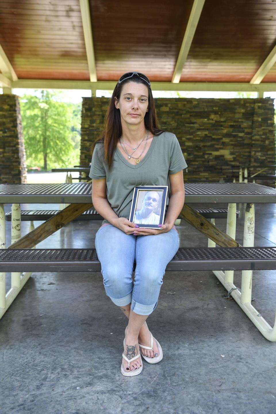 Jennifer Byrum holds a portrait of her father, Ricky Lewis, in New Harvest Park, Knoxville, Thursday, May 2, 2024.