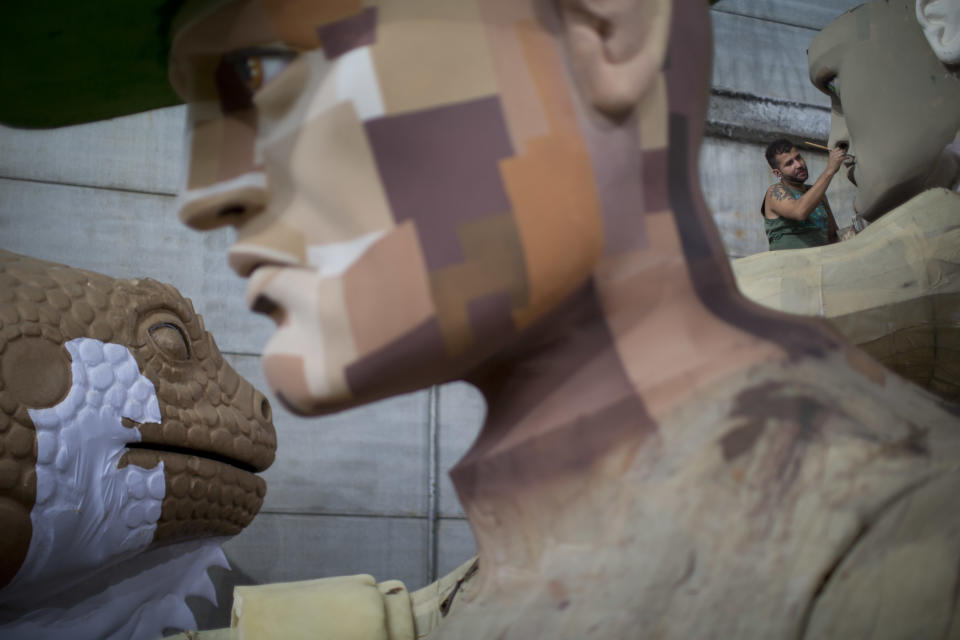 In this photo taken Tuesday, Jan. 22, 2013, a man paints a Carnival float sculpture at the Grande Rio Samba school in Rio de Janeiro, Brazil. Yet it's from warehouses like this one that Rio's over-the-top glitz-and-glam Carnival parades emerge, as they will Monday night for the final round of a two-day performance. The internationally renowned competition between 12 elite samba groups dazzles more than a billion spectators in person and on TV for two days, but it takes nearly a year and hundreds of workers, many of them volunteers, to pull each one together. (AP Photo/Felipe Dana)