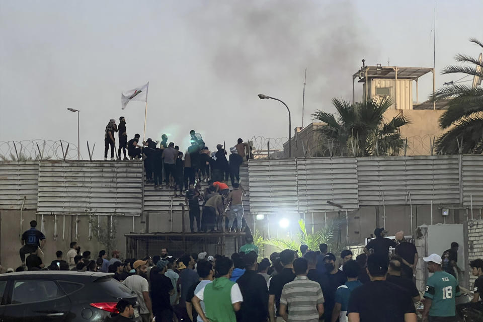 Manifestantes trepan un muro en la embajada sueca de Bagdad, el jueves 20 de julio de 2023. Manifestantes airados por la quema de un ejemplar del Corán irrumpieron en la embajada sueca en Bagdad, donde provocaron un pequeño incendio. (AP Foto/Ali Jabar)