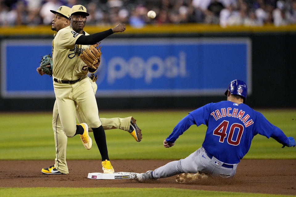 Arizona Diamondbacks' Geraldo Perdomo, left, forces out Chicago Cubs' Mike Tauchman (40) as he turns a double play on Ian Happ during the first inning of a baseball game, Friday, Sept. 15, 2023, in Phoenix. (AP Photo/Matt York)