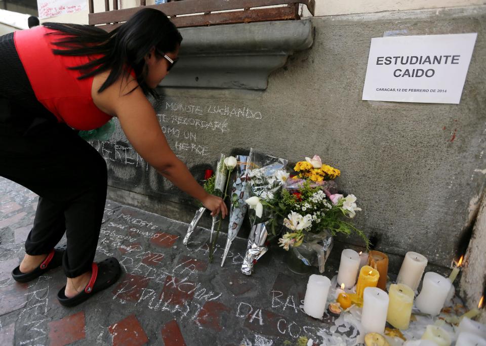 Una mujer coloca flores cerca del lugar donde el estudiante Bassil Da Costa fue muerto durante una manifestación de protesta contra el gobierno del presidente Nicolás Maduro en la esquina céntrica de la calle Monroy, Caracas, viernes 14 de febrero de 2014. A woman places flowers near the site where student Bassil Da Costa was killed during an anti-government protest on the corner of Monroy street in downtown Caracas, Venezuela, Friday, Feb. 14, 2014. Da Costa murió el miércoles cuando personas armadas dispararon a los manifestantes al final de una protesta mayormente pacífica. (AP Foto/Fernando Llano)