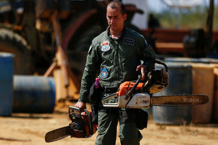 An agent of the Brazilian Institute for the Environment and Renewable Natural Resources, or Ibama, carries confiscated chainsaws during "Operation Green Wave" to combat illegal logging in Apui, in the southern region of the state of Amazonas, Brazil, July 29, 2017. REUTERS/Bruno Kelly