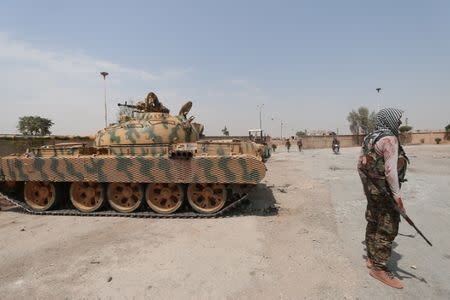 A Kurdish fighter from the People's Protection Units (YPG) carries his weapon as he stands past a tank in the Ghwairan neighborhood of Hasaka, Syria, August 22, 2016. REUTERS/Rodi Said