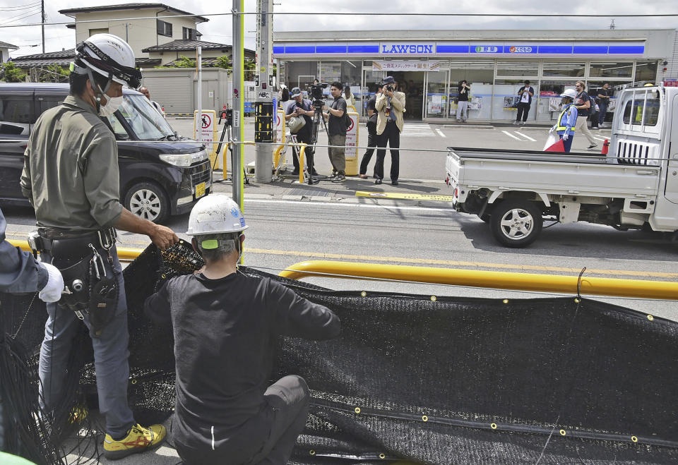 Workers set up a huge black screen on a stretch of sidewalk at Fujikawaguchiko town, Yamanashi prefecture, central Japan Tuesday, May 21, 2024. Just a few weeks ago, the town began setting up a huge black screen to block a view of Mount Fuji because tourists were crowding into the area to take photos with the mountain as a backdrop to a convenience store, a social media phenomenon known as “Mount Fuji Lawson” that has disrupted business, traffic and local life. (Kyodo News via AP)