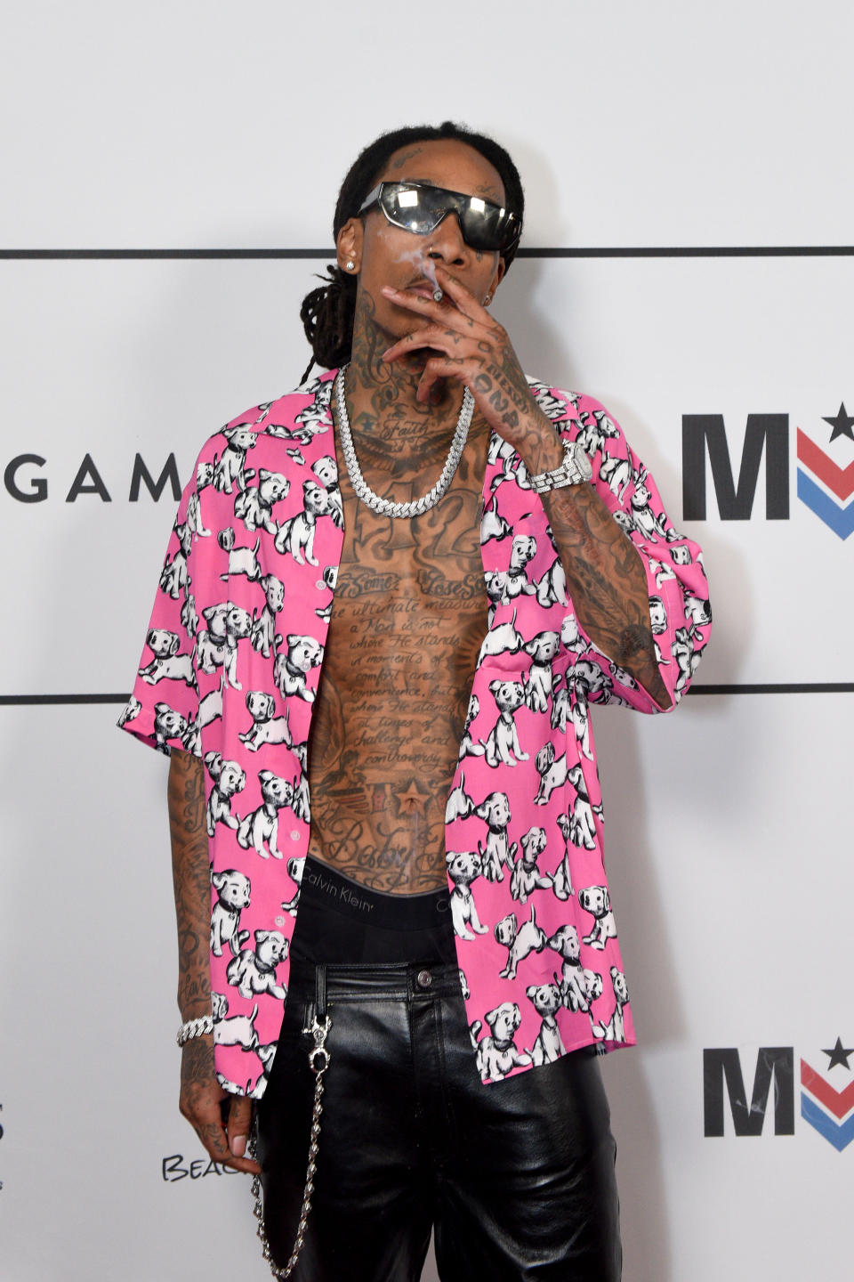 Wiz Khalifa in pink and white shirt, smoking with sunglasses on