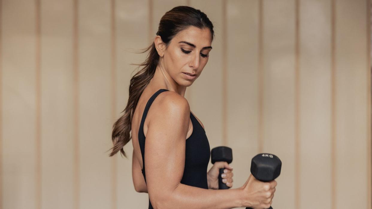 Woman flexing while holding dumbells 