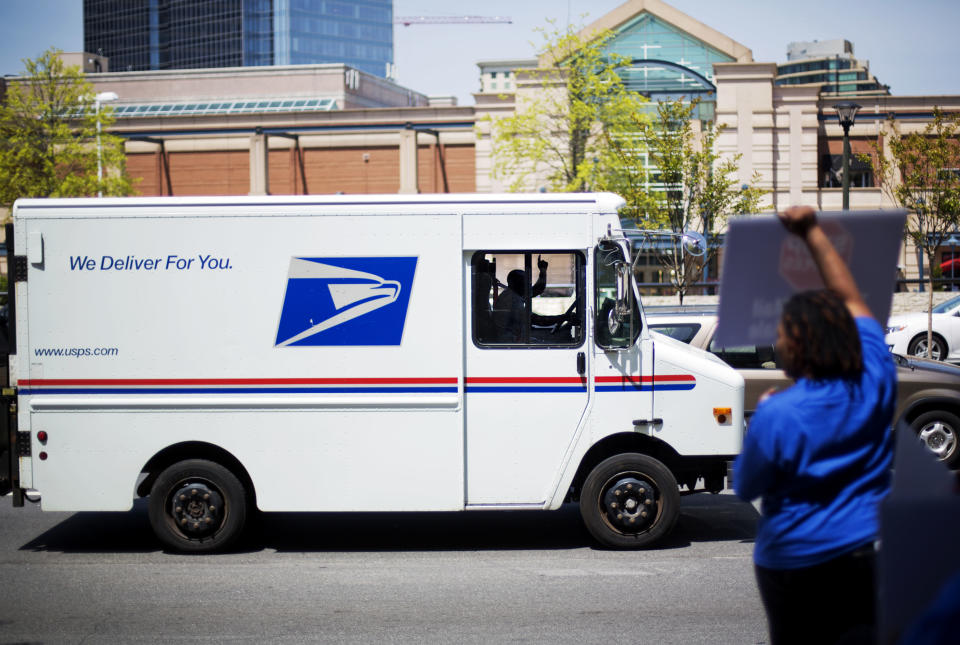 A U.S. Post Office driver gestures while passing a protest by fellow postal employees outside a Staples store, Thursday, April 24, 2014, in Atlanta. Thousands of postal workers picketed outside Staples stores nationwide Thursday to protest a pilot program that allows the office supply chain to handle U.S. mail. (AP Photo/David Goldman)