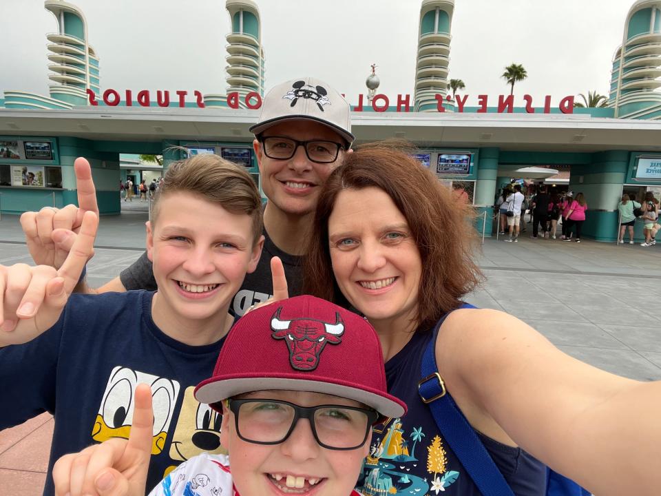 kari and her family holding up one finger in front of the entrance to hollywood studios at disney world