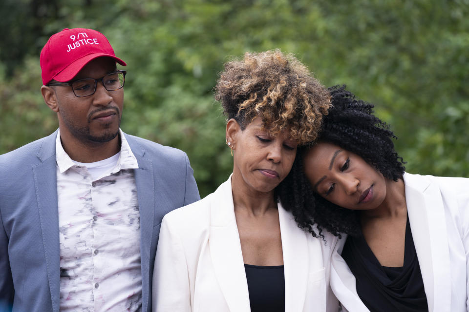 Terrease Aiken, right, leans against her mother, Kimberly, during a news conference at the North Plains Veterans Park in North Plains, Ore. Thursday, June 30, 2022. The Saudi Arabia-backed LIV Golf tour teed off Thursday, angering a group of families who lost loved ones on Sept. 11 and want the Saudi government held to account for the terrorist attacks. At left is Kanian Aiken. Kanian and Terrease's father, Terrance, was killed in the September 11th terrorist attacks in New York. Kimberly says her husband had just started his first week at Marsh & McLennan when the attacks occurred. Terrance Aiken was 30 years old when he was killed. (Beth Nakamura/The Oregonian via AP)