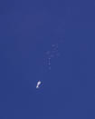 In this photo provided by Chad Fish, the remnants of a large balloon drift above the Atlantic Ocean, just off the coast of South Carolina, Saturday, Feb. 4, 2023. The downing of the suspected Chinese spy balloon by a missile from an F-22 fighter jet created a spectacle over one of the state’s tourism hubs and drew crowds reacting with a mixture of bewildered gazing, distress and cheering. (Chad Fish via AP)