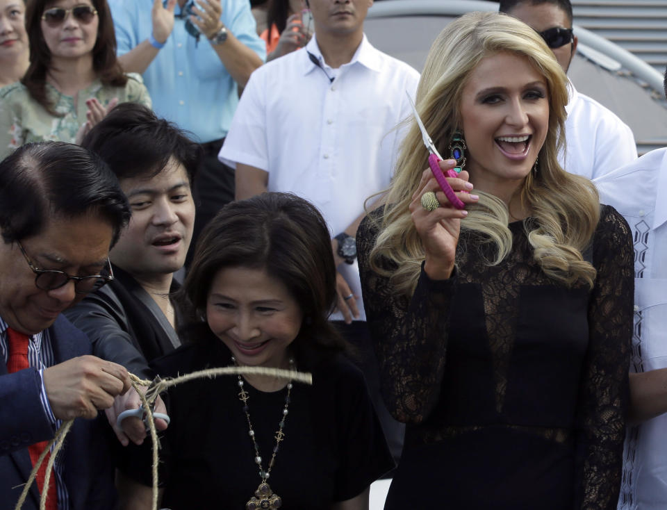 Paris Hilton, right, waves a pair of scissors after cutting the ribbon in the ceremony to unveil the Paris Beach Club, which she designed in collaboration with Philippine developer Century Properties, Thursday, March 13, 2014 at suburban Paranaque city, southeast of Manila, Philippines. Paris Hilton unveiled her first real estate project Thursday in metropolitan Manila and said she wants to follow in the footsteps of her great-grandfather and grandfather, who led a luxury hotel empire. (AP Photo/Bullit Marquez)