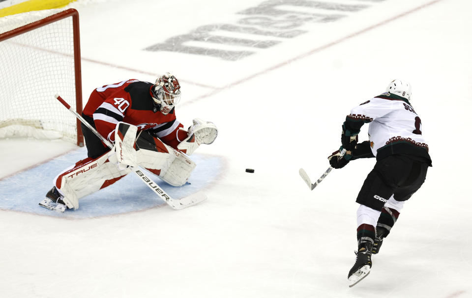 Arizona Coyotes center Nick Schmaltz, right, scores against New Jersey Devils goaltender Akira Schmid (40) during a shootout of an NHL hockey game Friday, Oct. 13, 2023, in Newark, N.J. (AP Photo/Noah K. Murray)