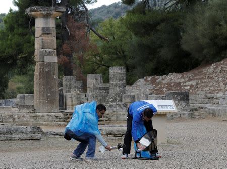 Olympics - Lighting Ceremony of the Olympic Flame Pyeongchang 2018 - Ancient Olympia, Olympia, Greece - October 24, 2017 Members of the organising staff remove plastic protecting the parabolic mirror from the rain during the Olympic flame lighting ceremony for the Pyeongchang 2018 Winter Olympics REUTERS/Alkis Konstantinidis