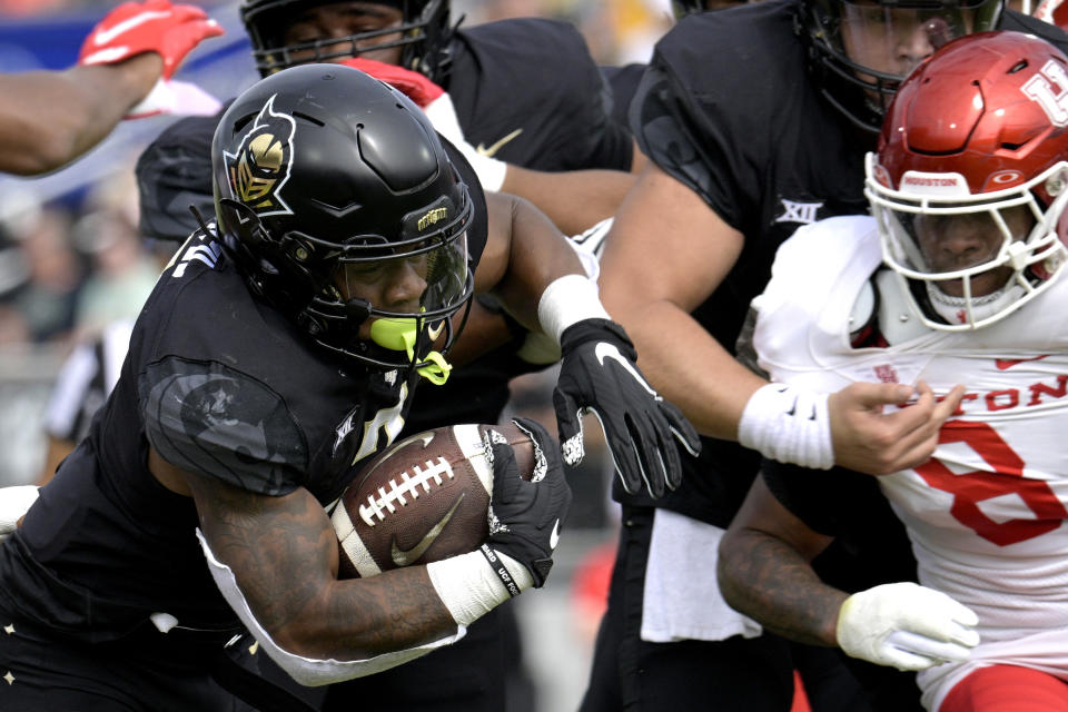 Central Florida running back RJ Harvey, left, rushes for yardage past Houston linebacker Malik Robinson (8) during the first half of an NCAA college football game, Saturday, Nov. 25, 2023, in Orlando, Fla. (AP Photo/Phelan M. Ebenhack)