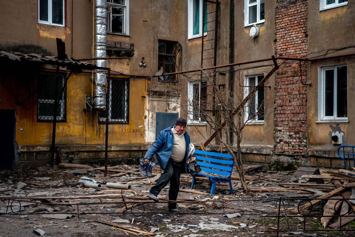 A man carries belongings he recovered from a damaged residential building after a missile strike in Chasiv Yar, Ukraine (Dimitar Dilkoff / AFP - Getty Images)