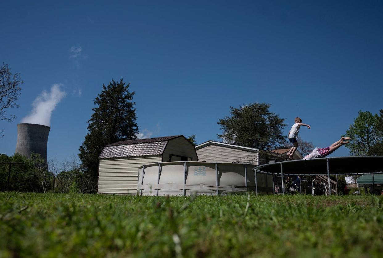 Kids jump on a trampoline as steam rises from a coal power plant in Adamsville, Ala., in 2021. <a href="https://www.gettyimages.com/detail/news-photo/kids-jump-on-a-trampoline-at-their-grandparents-home-as-news-photo/1232409457?adppopup=true" rel="nofollow noopener" target="_blank" data-ylk="slk:Andrew Caballero-Reynolds/AFP via Getty Images;elm:context_link;itc:0;sec:content-canvas" class="link "> Andrew Caballero-Reynolds/AFP via Getty Images</a>