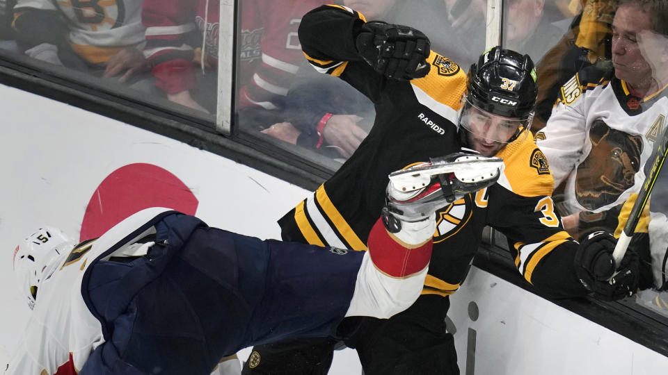 Boston Bruins center Patrice Bergeron (37) avoids taking a skate to the face after checking Florida Panthers defenseman Aaron Ekblad, left, during the first period of Game 5 in the first round of the NHL hockey playoffs, Wednesday, April 26, 2023, in Boston. (AP Photo/Charles Krupa)