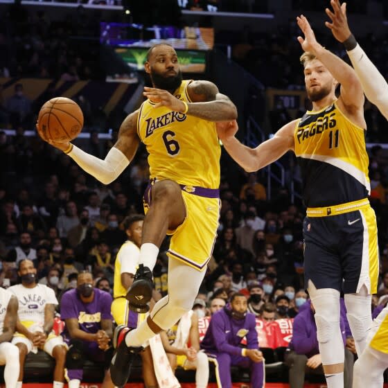 Lakers forward LeBron James leaps on the baseline to pass abasing Indiana Pacers forward Domantas Sabonis.