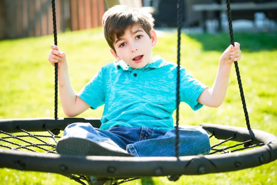 Ryder Harris plays on his home swing set with the assistance of his father Chris Harris, on Thursday, April 13, 2023 in Indiana. Ryder has a lifelong disorder called Polymicrogyria (PMG,) and epilepsy. The Harris family hopes a service dog would help to predict Ryder's seizures. 