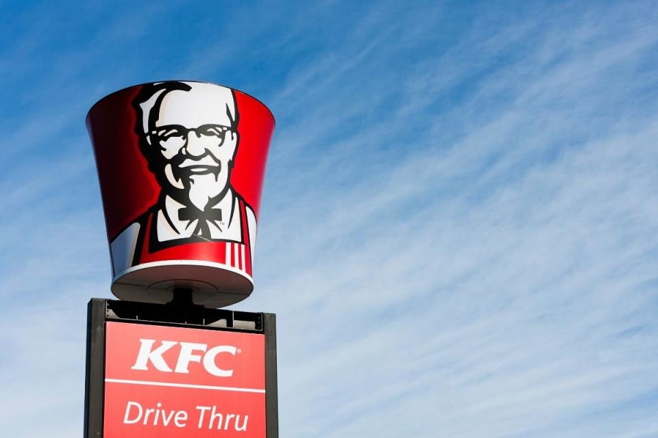 KFC drive-thru sign against cloudy blue sky