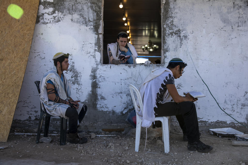 Israeli settlers pray in a synagogue at the recently established wildcat Jewish outpost of Eviatar, near the northern Palestinian West Bank town of Nablus, Monday, June 28, 2021. Palestinians say the outpost was established on private farmland. Israeli media said Monday that the government was working on reaching a compromise with the settlers that would see the outpost evacuated in the coming days. (AP Photo/Ariel Schalit)