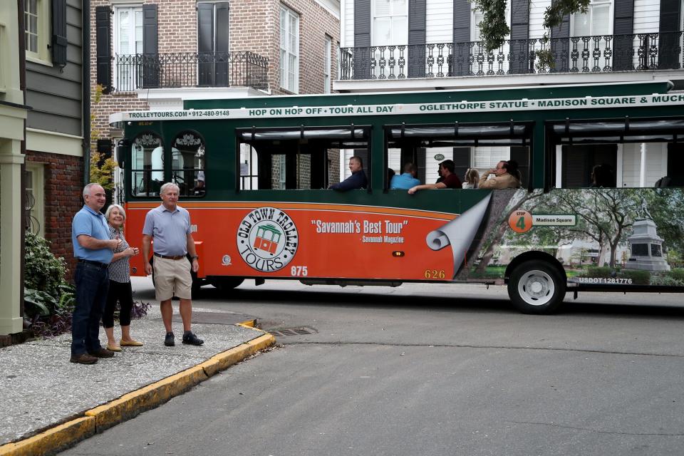 David McDonald, president of the Downtown Neighborhood Association, Nancy Radke, and Steve Mott stand on the corner of East Bryan and Houston Streets as a trolley tour passes on Wednesday, October 11, 2023. About 13 trollies, from different companies, passed by in a span of 20 minutes.