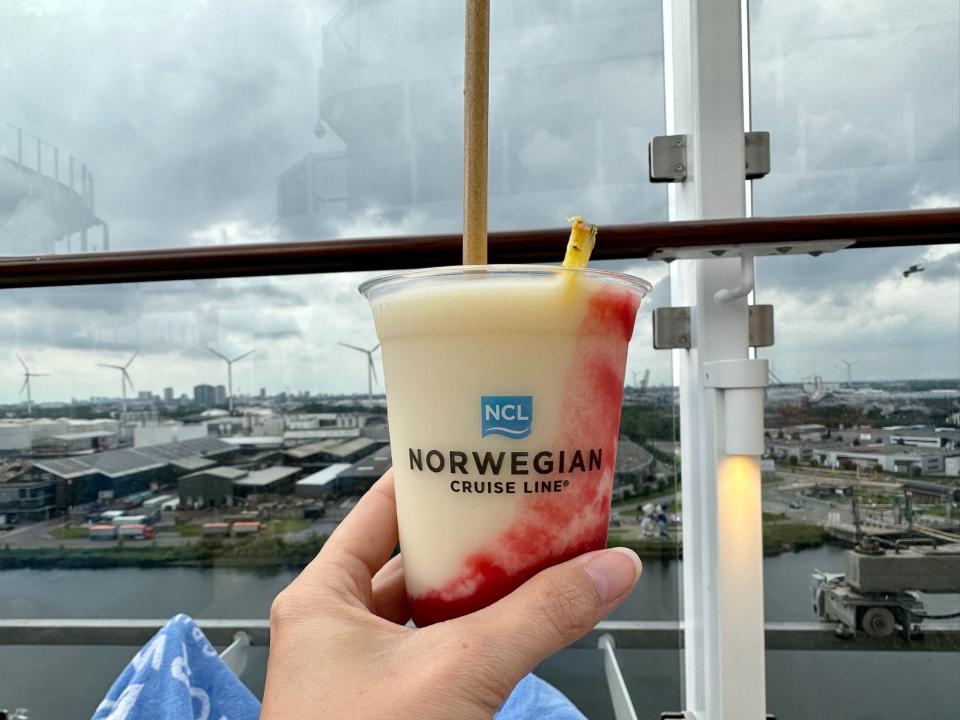 Hand holding a frosty beverage on a cruise with Norwegian Cruise printed on the cup