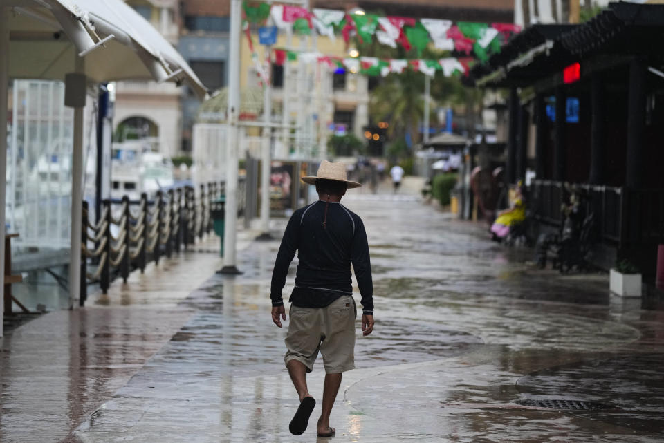 A tourist walks along the harbor with shops and restaurants closed by the arrival of the hurricane Norma in Cabo San Lucas, Mexico, Friday, Oct. 20, 2023. Hurricane Norma is heading for the resorts of Los Cabos at the southern tip of Mexico's Baja California Peninsula, while Tammy grew into a hurricane in the Atlantic. (AP Photo/Fernando Llano)