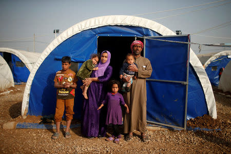 Displaced Iraqi Abdullah Mustafa, 38, poses for a photograph with his family at Hammam al-Alil camp south of Mosul, Iraq, March 29, 2017. Mustafa, a construction worker, says the family house was shelled in a mortar attack while they were inside but fortunately no one was hurt. Two days later, they fled their home. REUTERS/Suhaib Salem