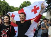 A man holds a Georgian national flags as opposition demonstrators gather in front of the Georgian Parliament building in Tbilisi, Georgia, Saturday, June 22, 2019. Demonstrators denounced the government Friday as overly friendly to Russia and calling for a snap parliamentary election. (AP Photo/Shakh Aivazov)