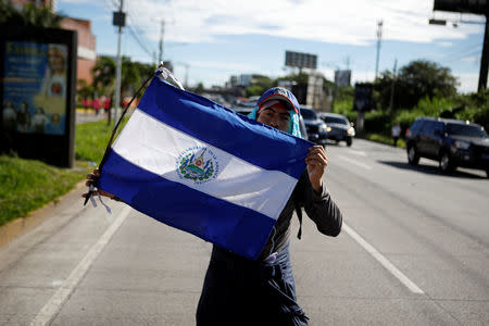 A man holds a Salvadoran flag as a caravan of migrants departs from El Salvador en route to the United States, in San Salvador, El Salvador, October 28, 2018. REUTERS/Jose Cabezas