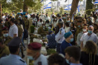 Civilians and soldiers gather by graves of Israeli soldiers during a Memorial Day ceremony for fallen soldiers and victims of attacks, at the military cemetery at Mount Herzl, in Jerusalem, Wednesday, April 14, 2021. On Israel Memorial Day, the most solemn day on Israel's national calendar, people stood at attention while a two-minute siren sounded around the country and held remembrance ceremonies at cemeteries. (AP Photo/Ariel Schalit)