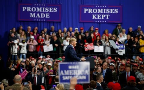 Donald Trump speaks against a backdrop of posters declaring: "Promises Made, Promises Kept" - Credit: AP