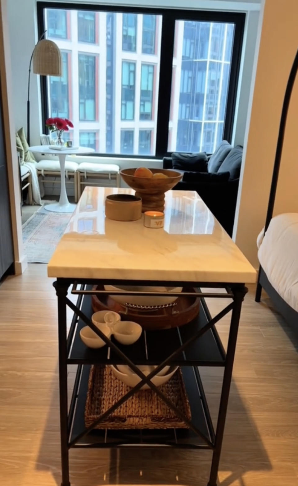 Kitchen island with bowls and a tray facing a living area with large windows