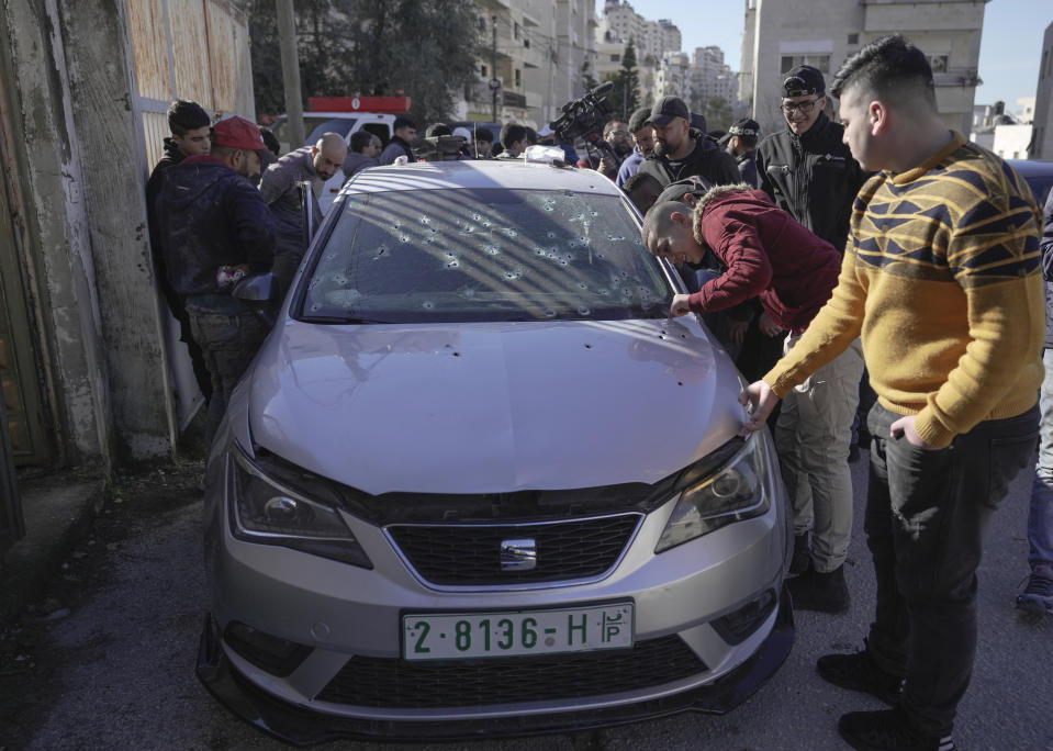 CORRECTION - REMOVES REFERENCE TO A CLASH - People inspect bullet holes in the car where three Palestinians were killed by Israeli security forces in the occupied West Bank city of Nablus, Tuesday, Feb. 8, 2022. Israel said it killed three Palestinian militants in Nablus who had been responsible for recent shooting attacks. (AP Photo/Majdi Mohammed)