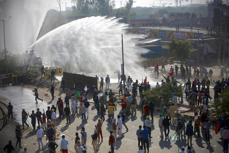 Policemen use water cannon to prevent protesting farmers from moving ahead towards Delhi, at the border between Delhi and Haryana state, Friday, Nov. 27, 2020. Thousands of agitating farmers in India faced tear gas and baton charge from police on Friday after they resumed their march to the capital against new farming laws that they fear will give more power to corporations and reduce their earnings. While trying to march towards New Delhi, the farmers, using their tractors, cleared concrete blockades, walls of shipping containers and horizontally parked trucks after police had set them up as barricades and dug trenches on highways to block roads leading to the capital. (AP Photo)