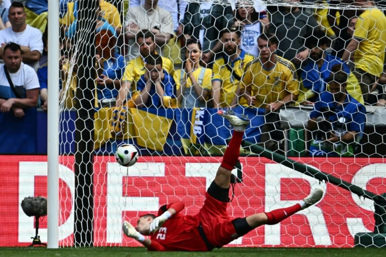 El portero ucraniano Andriy Lunin no logra atajar el disparo del rumano Razvan Marin que supuso el segundo gol en la derrota 3-0 de Ucrania en partido del grupo E de la Eurocopa, en Múnich el 17 de junio de 2024 (Fabrice COFFRINI)