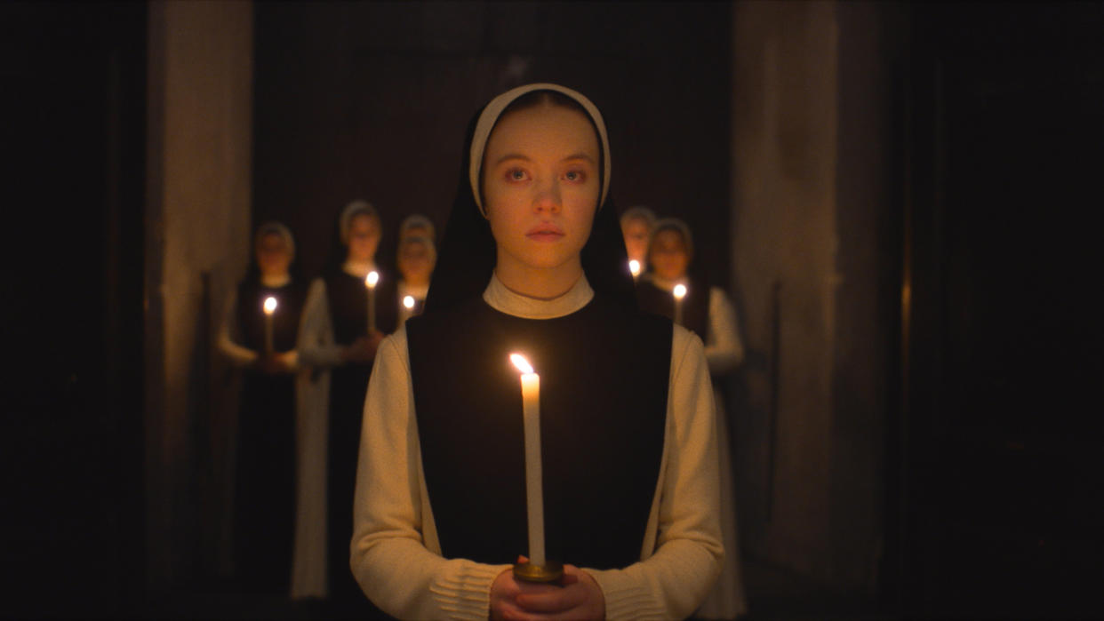  Sydney Sweeney walks in darkness with a lit candle in her hands in Immaculate. 