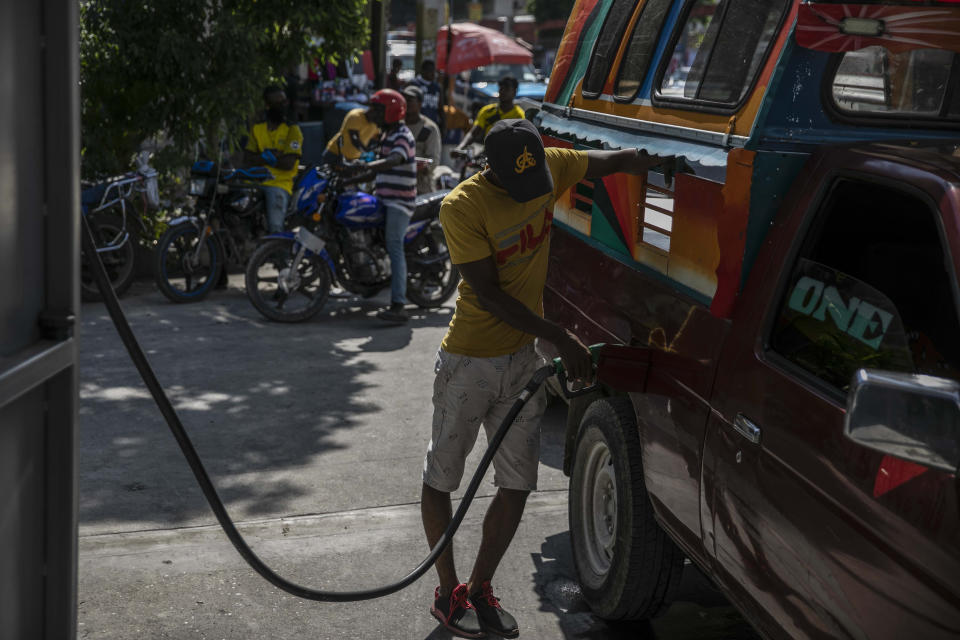 Un hombre llena el tanque de su vehículo en una gasolinera en Puerto Príncipe, Haití, el sábado 12 de noviembre de 2020, tras la reapertura de esos establecimientos de combustible. (AP Foto/Odelyn Joseph)