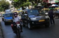 In this photo taken on April 3, 2014, Uber driver Dinish Karamsesula, right, whose employer partnered with the company in Mumbai, drives his black SUV past traditional black-and-yellow licensed cabs in Mumbai, India. Riding on its startup success and flush with fresh capital, taxi-hailing smartphone app Uber is making a big push into Asia. The company has in the last year started operating in 18 cities in Asia and the South Pacific including Seoul, Shanghai, Bangkok, Hong Kong and five Indian cities. (AP Photo/Rafiq Maqbool)