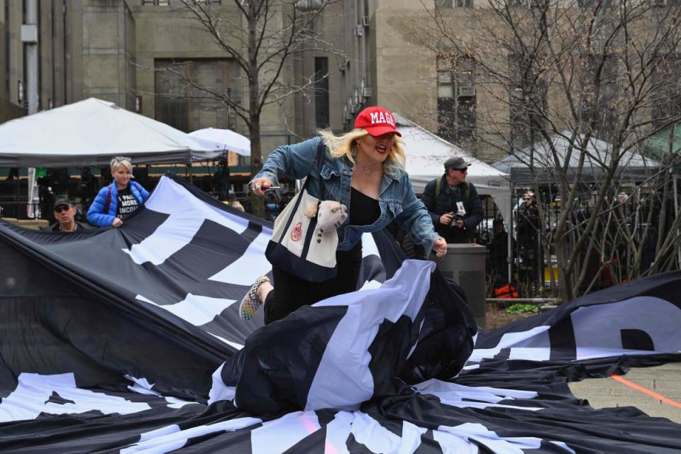 A supporter of former US president Donald Trump tears up an anti-Trump banner during a protest outside of Manhattan Criminal Court in New York City (AFP/Getty)