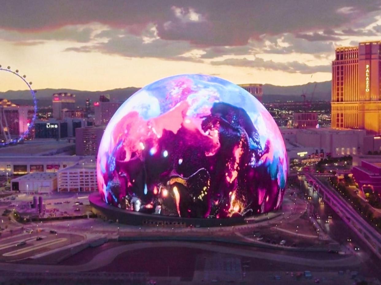 A giant glowing dome with a wheel and a large hotel in the background