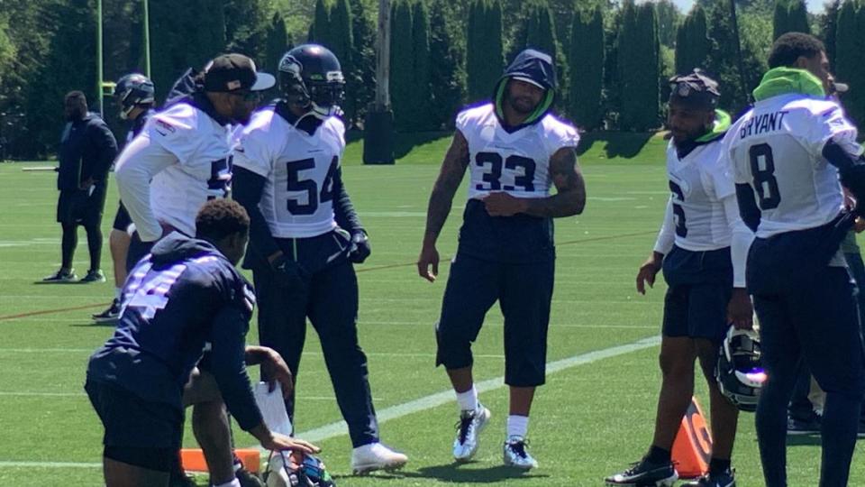 Jamal Adams (33) and Jordyn Brooks (56) talk to teammates Bobby Wagner (54) and Quandre Diggs (6) on the first day of the Seahawks’ mandatory minicamp at team headquarters in Renton June 6, 2023. Adams and Brooks had been in Texas all spring with their coaches’ OK rehabilitating from major injuries.