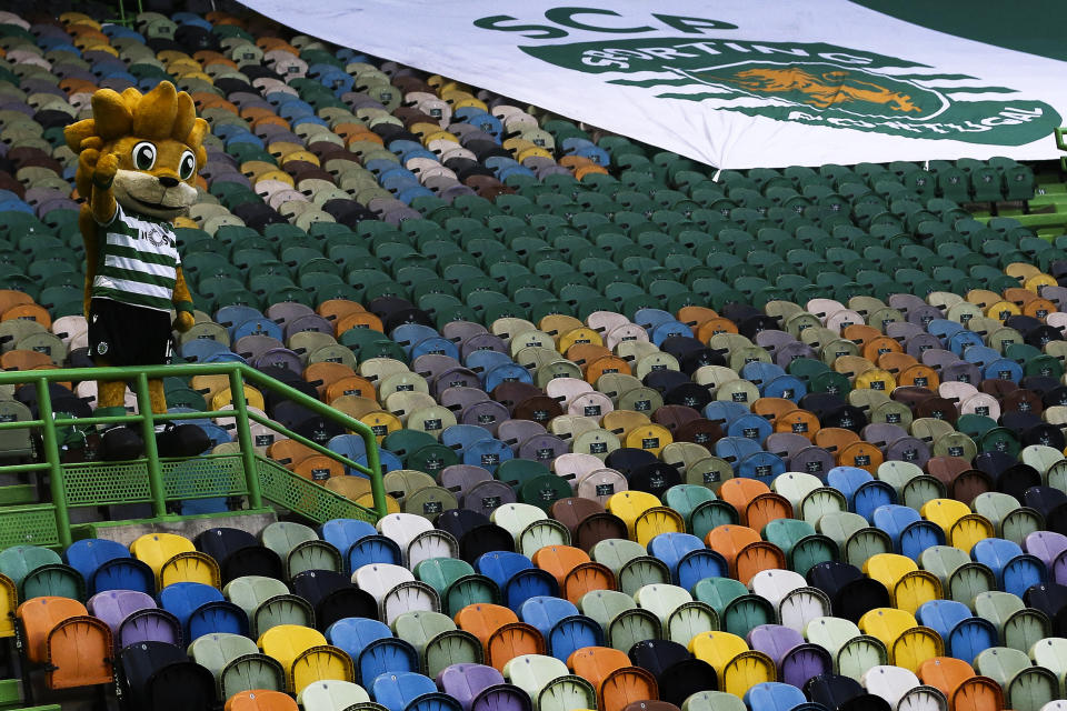 Sporting's mascot lion waves from the empty stands during the Portuguese League soccer match between Sporting CP and Pacos de Ferreira at the Jose Alvalade stadium in Lisbon, Portugal, Friday, June 12, 2020. The Portuguese League soccer matches are being played without spectators because of the coronavirus pandemic. (Antonio Cotrim/Pool via AP)