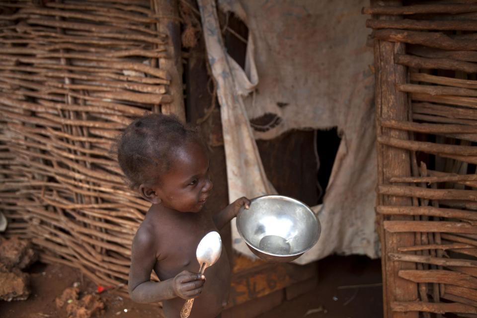 In this Tuesday, March 25, 2014 photo, with spoon and bowl in hand, 2-year-old Rosemika Beltinor toddles on the perimeters of her home in search of food, in Bombardopolis, in northwest Haiti. “The rain isn’t falling. I can’t feed my family,” said Rosemika's father, Jean-Romain Beltinor. “Sometimes you spend a couple of days without food.” (AP Photo/Dieu Nalio Chery)