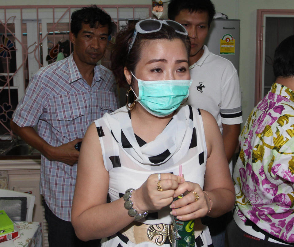 In this photo taken Thursday, Oct. 11 2012, Jiratha Saraban, 37, an unlicensed practitioner, is watched by two plainclothes police officers during a raid at her house that is used as a backdoor beautician clinic in Bangkok. Thailand is swarming with cheap but risky cosmetic clinics. The death this month of a 33-year-old aspiring model from a botched collagen injection has focused nationwide attention on the illegal beauty industry and intensified a government crackdown. (AP Photo/Apichart Weerawong)